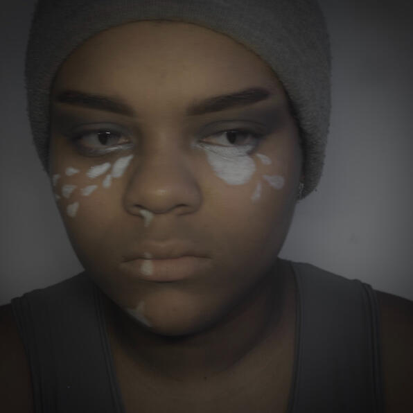 a black man in grey clothing. mist pours in tears from his nose and eyes. his clouded eyes look to the side.
